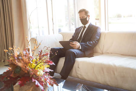 Calm businessman with his gadget in the hotel lobbyの写真素材