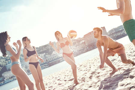 Time with friends. Group of young people playing volleyball on the beachの写真素材