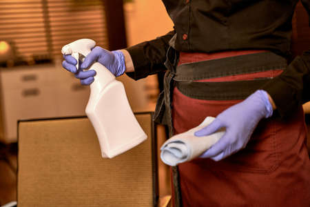 Hands of waitress with folded cleaning rag and spray