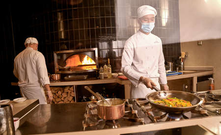 Asian cook keeping peppers in pan over stove burnerの写真素材