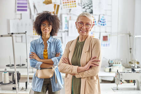 Positive dressmakers pose for camera together in light fashion studioの写真素材