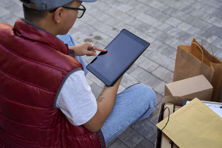 Checking adress of a client. Male courier looking at map or usinの写真素材