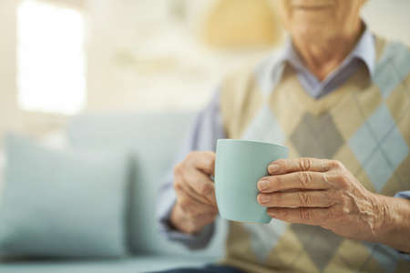 Pensioner resting at home with a cup of hot teaの写真素材