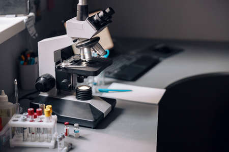 Microscope, rack with test tubes and vials on table in laboratoryの写真素材