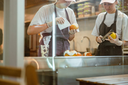 Professional confectioners make buns with cream and grated lemon zest in bakeryの写真素材