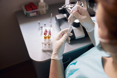 Female lab tech takes sample from test tube to research material at workplace with modern equipmentの写真素材