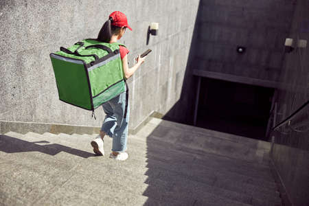 Delivery service worker checking order via mobile phone outdoorsの写真素材