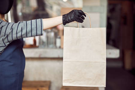 Woman cafe worker serving unrecognizable customer outdoorsの写真素材