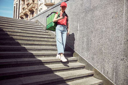 Asian young woman delivering takeout food to customer outdoorsの写真素材