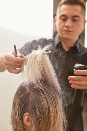 Skillful hairdresser cutting woman hair in beauty salonの写真素材