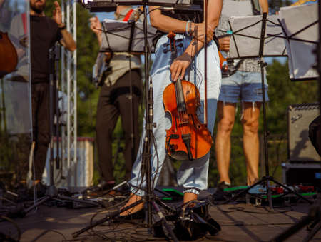 Female violinist standing near music stand outdoors