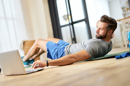 Athletic young man using laptop during morning trainingの写真素材
