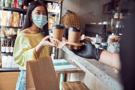 Happy female taking coffee from waitress in cafeの写真素材