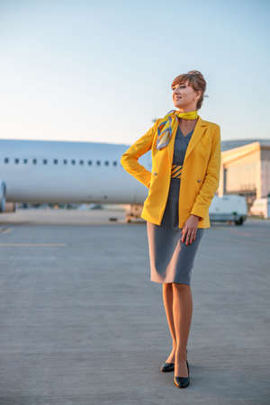 Joyful stewardess or air hostess standing outdoors at airportの写真素材
