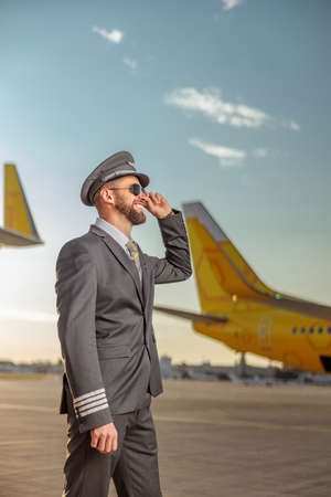 Cheerful aircraft pilot standing outdoors at airfieldの写真素材