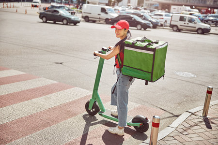 Asian courier with backpack delivering takeaway food to customer outdoorsの写真素材