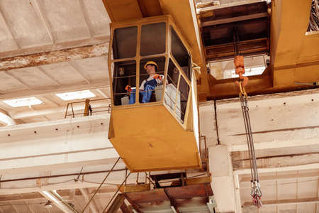Male worker sitting in operator cabin of overhead craneの写真素材
