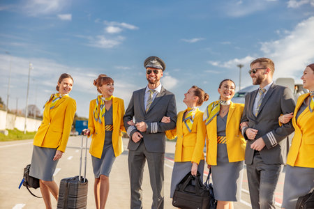 Cheerful aircrew with travel bags standing outdoors at airfield