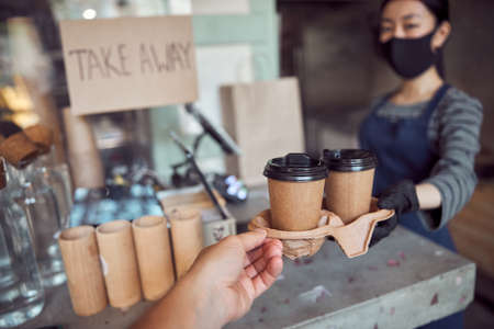 Female worker giving customer delicious coffee in modern cafe