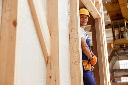 Smiling male worker standing inside wooden construction cabin