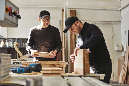 We love your company. Busy carpenters in uniform working with wood.の写真素材