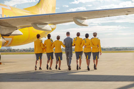 Airline workers walking near airplane at airportの写真素材
