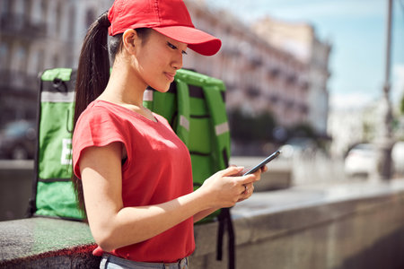 Delivery service worker using cellphone in cityの写真素材