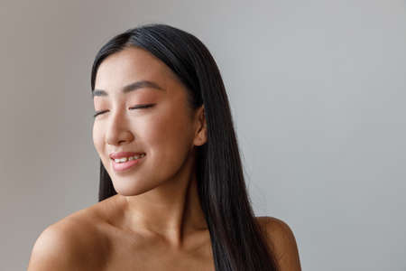 Smiling Asian young woman standing in studioの写真素材