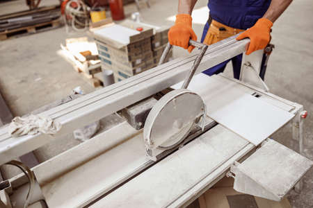 Male worker using sawing machine in workshop