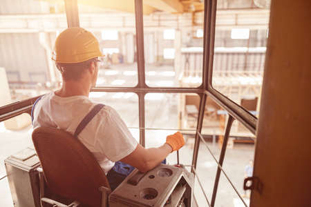 Male worker sitting in operator cabin of overhead craneの写真素材