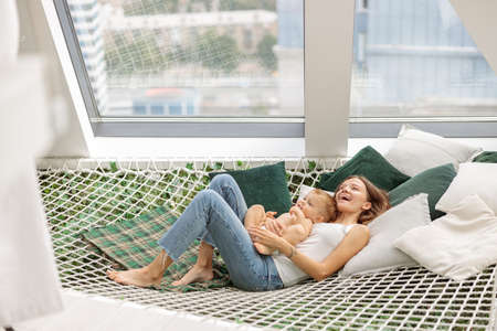 Happy young mother and child on a mesh hammockの写真素材