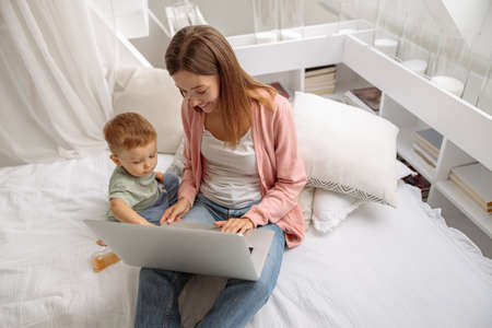 Happy young mom with her baby using latopの写真素材