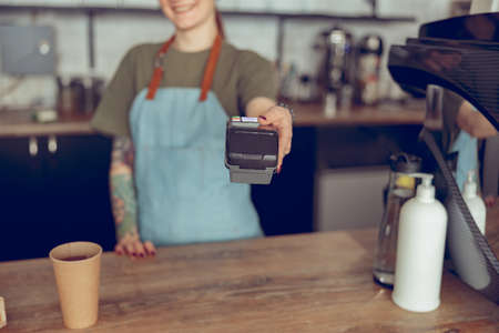 Female barista using terminal for contactless payment in cafeteriaの写真素材