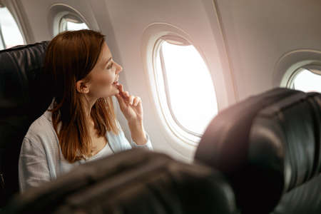 Cheerful woman looking out the window in airplaneの写真素材
