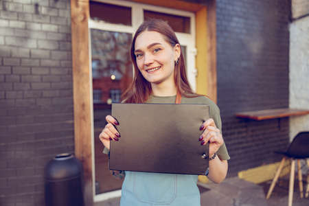 Cheerful female barista holding clipboard outside coffee shopの写真素材