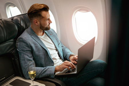 Male passenger working on laptop in airplane