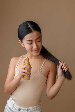 Asian young woman applying hair spray on her hairの写真素材
