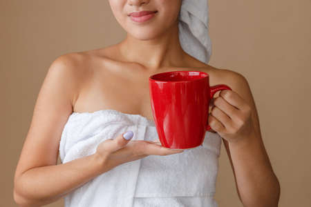 Asian young woman with cup of coffee standing in studioの写真素材