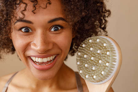 Happy lady representing massage brush in studioの写真素材