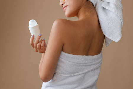 Young woman with deodorant standing in studioの写真素材