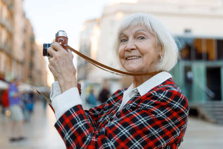 Confident elderly female with happy face posing outdoorsの写真素材