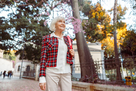 Senior woman looking away while standing in cityの写真素材