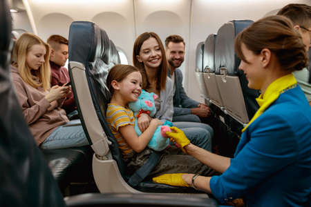 Family with child talking with stewardess in airplaneの写真素材
