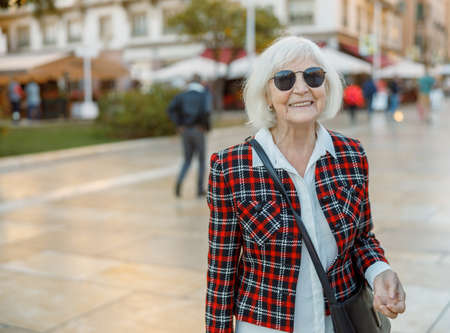 Happy pensioner female walking outdoors in townの写真素材