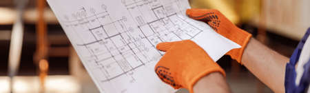 Male worker hands in gloves holding architectural planの写真素材