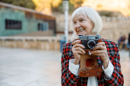 Senior woman looking away while standing in cityの写真素材