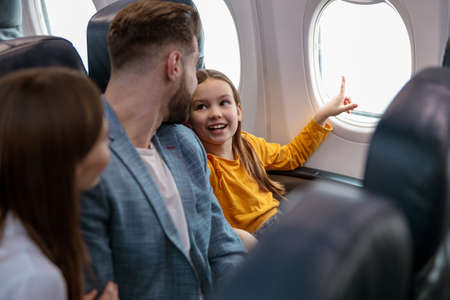 Little girl with parents traveling on airplaneの写真素材