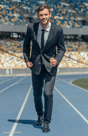Front view photo of young businessman running on race trackの写真素材