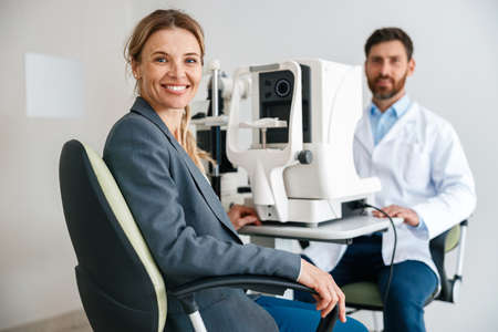 Woman happy with result after checking eyesight in ophthalmology clinicの写真素材