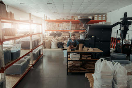 Business owner of small coffee roasting factory working on his workplace
